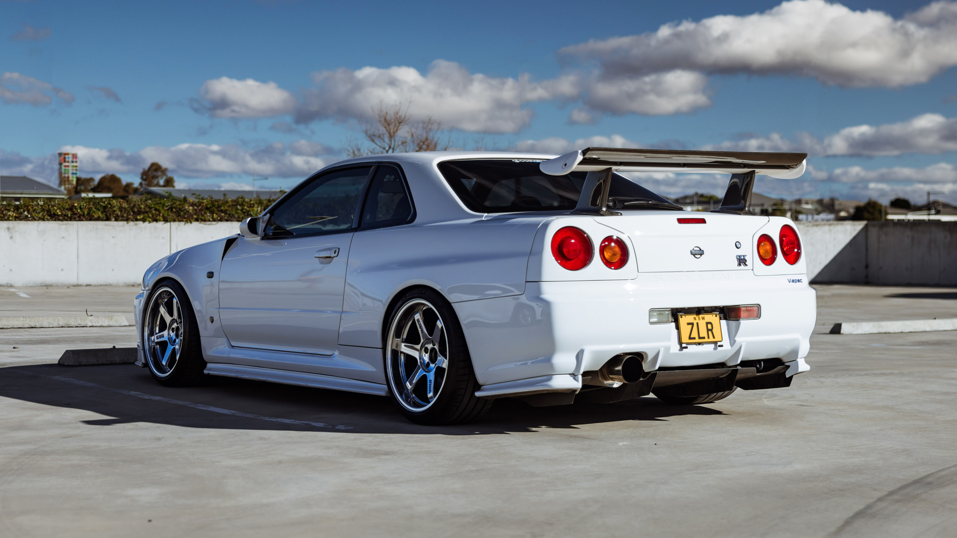 White Nissan Skyline R34 GTR looking at back with car facing left
