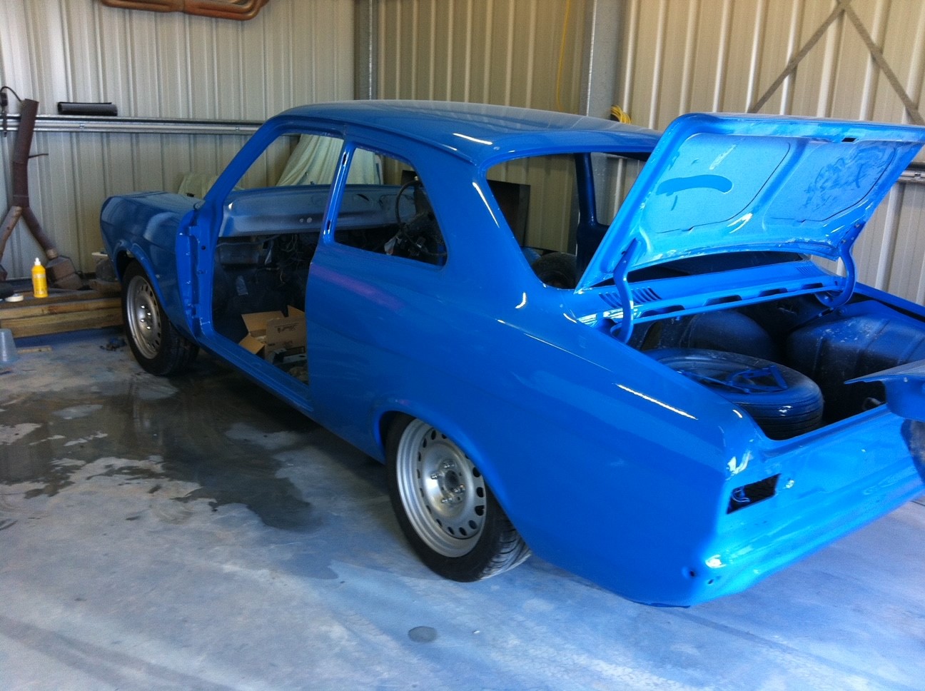 Laid up blue 1975 Ford Mk 1 Escort Coupe facing left and backwards