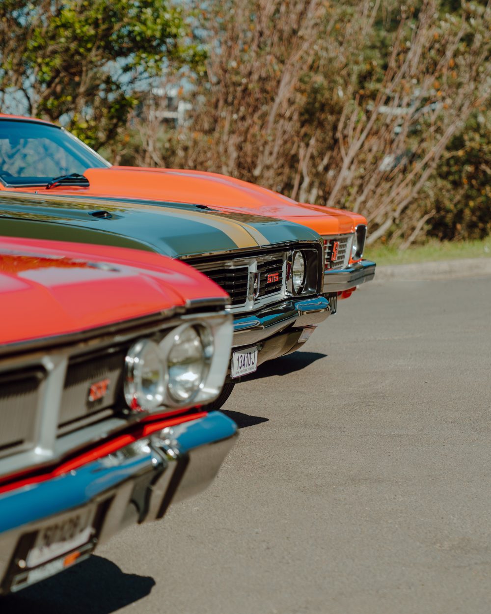 From front: red 1970 Ford Falcon XY GT, green 1969 Holden Monaro GTS Coupe, orange 1976 Holden Torana