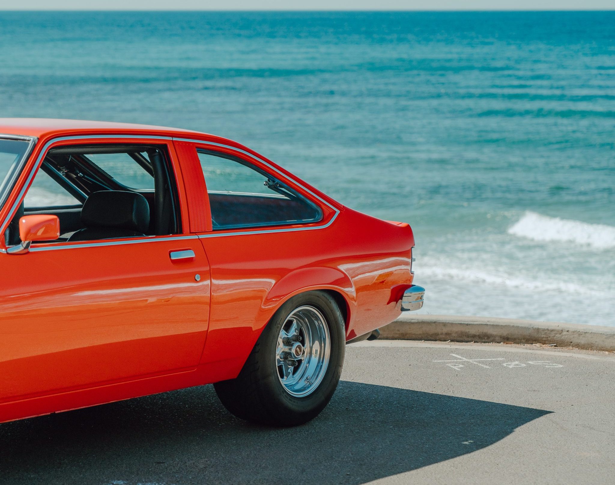 Orange 1976 Holden Torana looking the back with beach in background