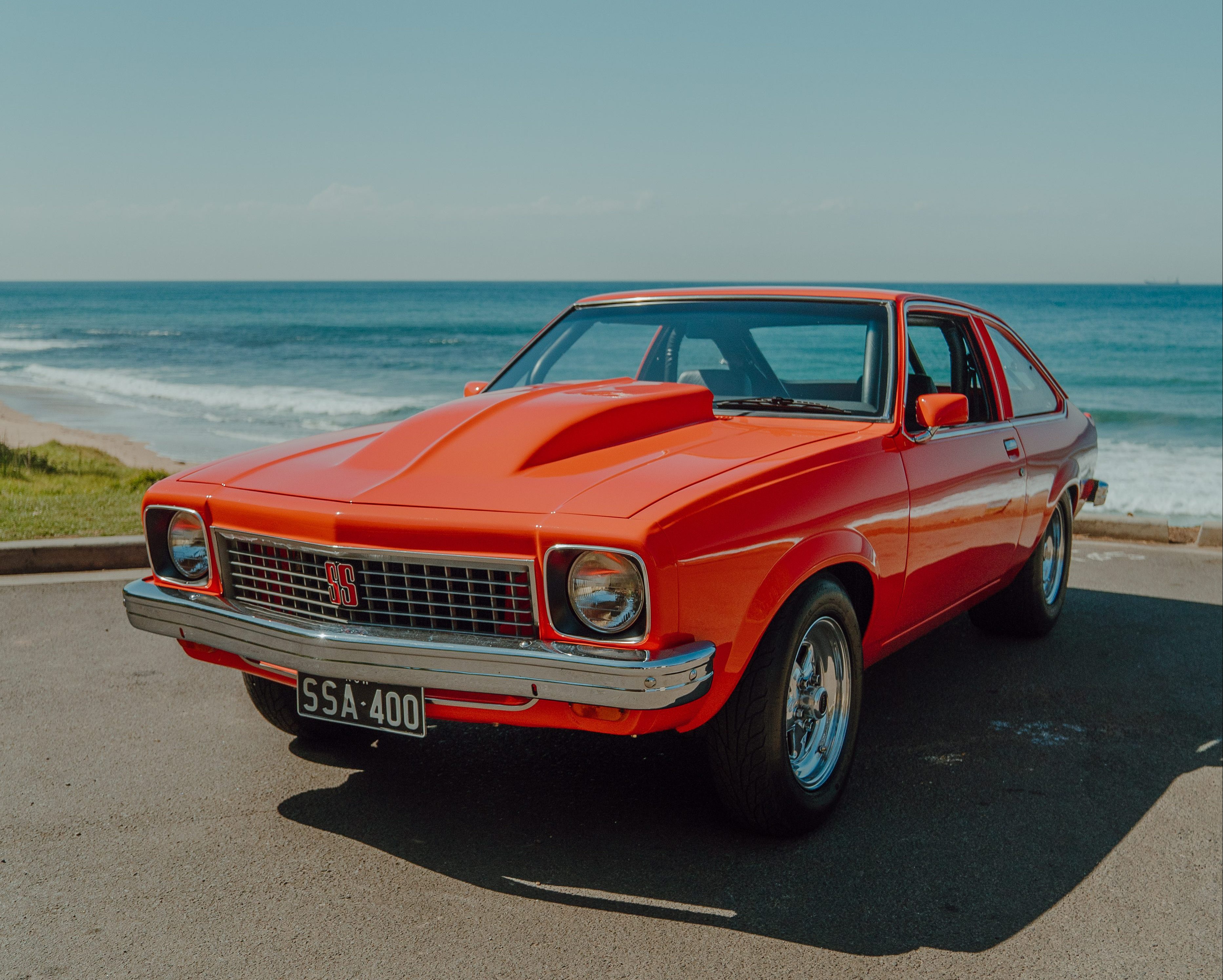 Orange 1976 Holden Torana with reverse cowl scoop at the beach